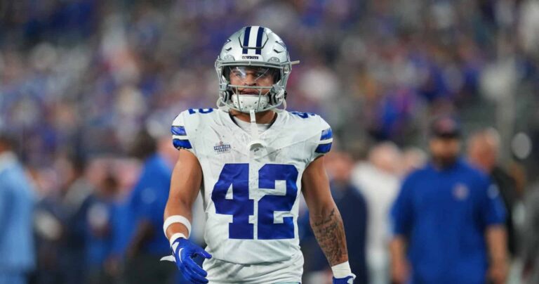 Football player in a white and blue uniform with number 42 walking on the field.