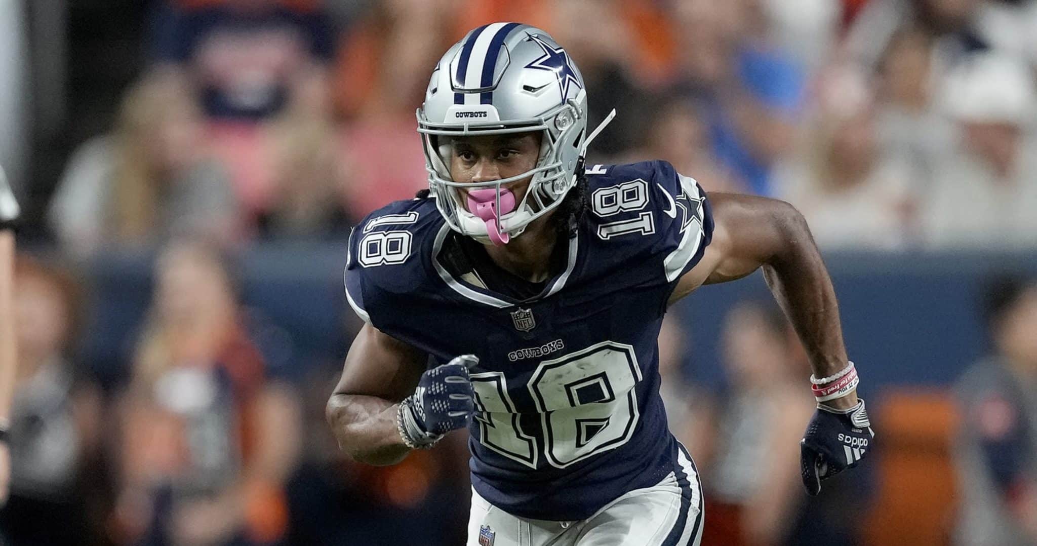 A football player wearing a Dallas Cowboys uniform, number 18, runs on the field during a game.