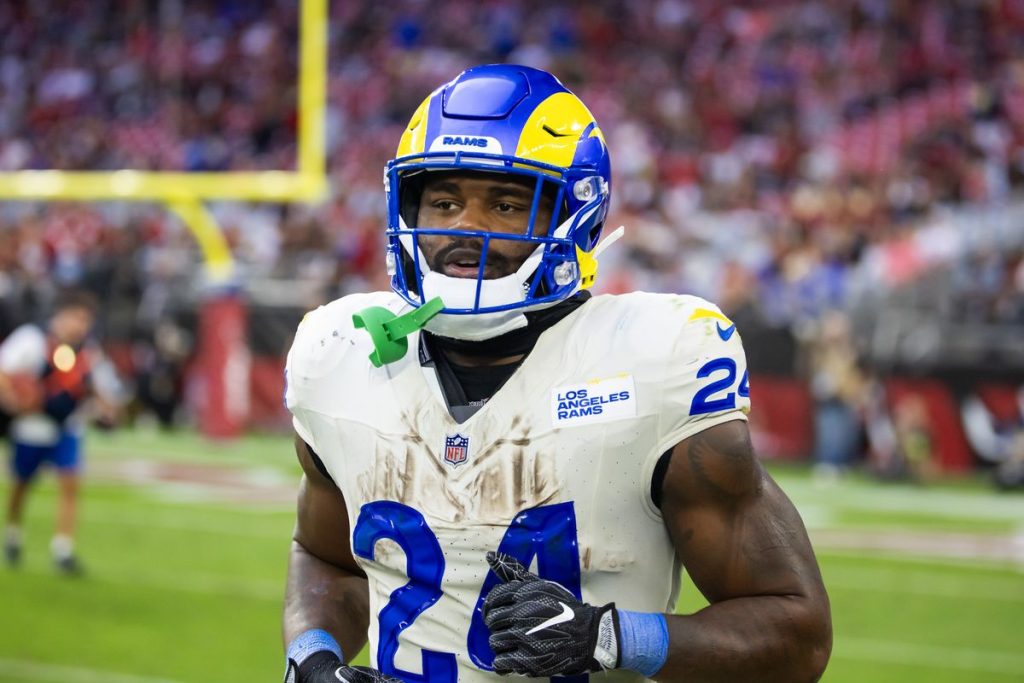 A Los Angeles Rams football player wearing a blue and yellow helmet and white uniform on the field during a game.