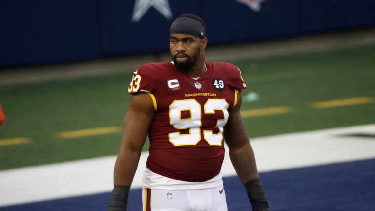 Football player in a red jersey with number 93 stands on the field with a serious expression.